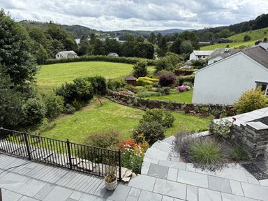 A garden with a stone patio and grass lawn at Estcote Roger Ground near Hawkshead