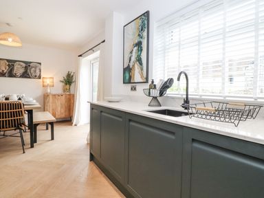 A kitchen with a sink and drying rack next to a dining area with a table and chairs at Rydal Rock in Ambleside