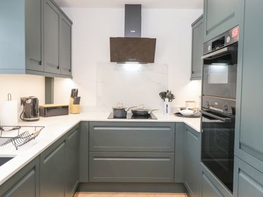 A kitchen with grey cabinets a black stove two pots and kitchen utensils at Rydal Rock in Ambleside