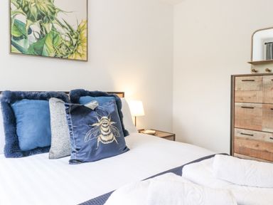 A bed with blue and gray pillows and white towels on top with a wooden dresser and lamp in a bedroom at Rydal Rock Ambleside