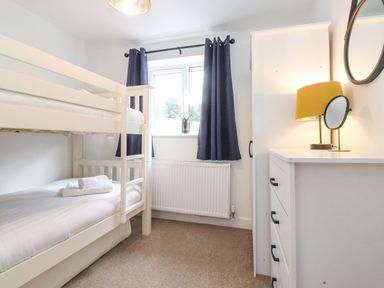 A bedroom with bunk beds towels on bed window with curtains dresser with lamp and mirror at Rydal Rock Ambleside