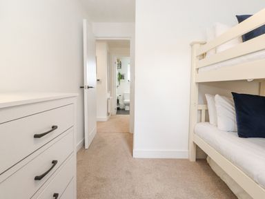 A bedroom with a bunk bed and dresser with an open door leading to a bathroom at Rydal Rock in Ambleside