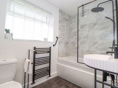 A bathroom with a toilet a towel rack a bathtub with a shower and a sink at Rydal Rock in Ambleside