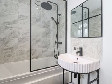 A bathroom with a bathtub shower combination and a white sink with black fixtures at Rydal Rock Ambleside
