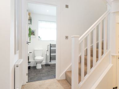 A hallway with carpeted stairs and a view into a bathroom with a toilet and a towel rack at Rydal Rock in Ambleside
