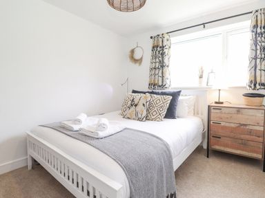 A bedroom with a white bed a wooden bedside table and floral curtains at Rydal Rock in Ambleside