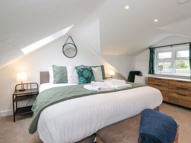A bedroom with a large bed bedside tables lamps a wooden dresser and a window at Rydal Rock in Ambleside