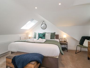 A bedroom with a bed and green cushions under a skylight at Rydal Rock in Ambleside