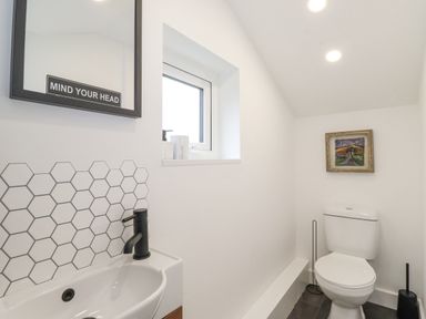 A small bathroom with a toilet sink mirror and window at Rydal Rock in Ambleside