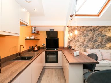 A kitchen with wooden countertops and black sink next to a lounge area with sofa and hanging lights at Fenty's in Bowness-On-Windermere