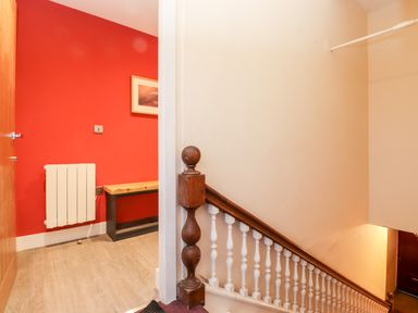 A stairway next to a room with a red wall a bench and a radiator at Fenty's in Bowness-On-Windermere