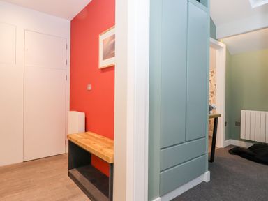 A small hallway with a wooden bench against a red wall and a blue cabinet next to a doorway at Fenty's in Bowness-On-Windermere