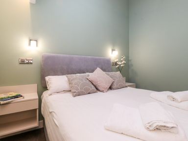 A bedroom with a bed with pillows bedside tables lamps and folded towels at Fenty's in Bowness-On-Windermere