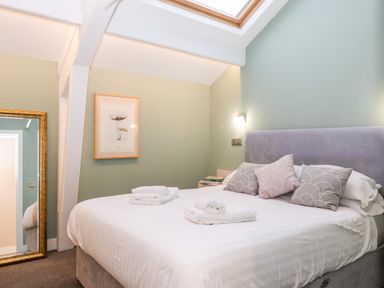 A bedroom with a double bed white linens and pillows a framed picture a mirror and a skylight at Fenty's in Bowness-On-Windermere