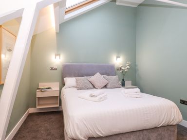 A bedroom with a double bed pillows towels bedside tables and wall lights at Fentys in Bowness-On-Windermere