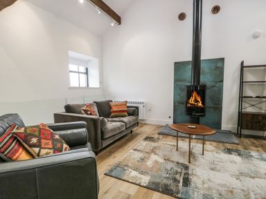 A living room with sofas a wooden coffee table a rug and a fireplace at Bank Hurst Coach House in Ulverston