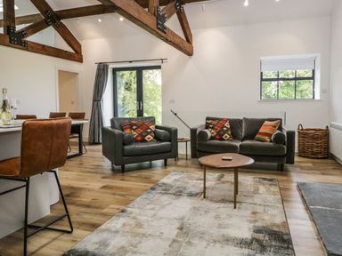 A living room with leather armchairs a sofa and a wooden table at Bank Hurst Coach House in Ulverston