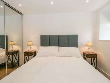 A bedroom with a bed with a dark headboard and two bedside tables with lamps at Bank Hurst Coach House in Ulverston