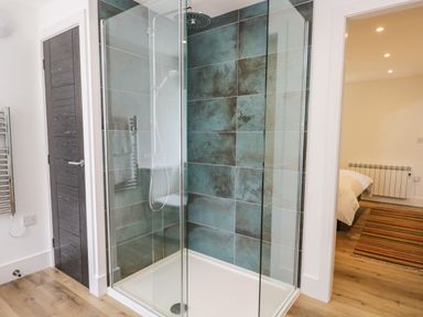 A bathroom with a glass shower enclosure and a tiled shower wall at Bank Hurst Coach House in Ulverston
