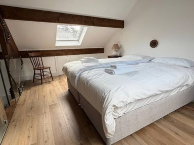 A bedroom with two beds and a chair at Bank Hurst Coach House in Ulverston