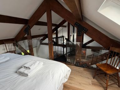 A bedroom with a bed and wooden chairs at Bank Hurst Coach House, Ulverston