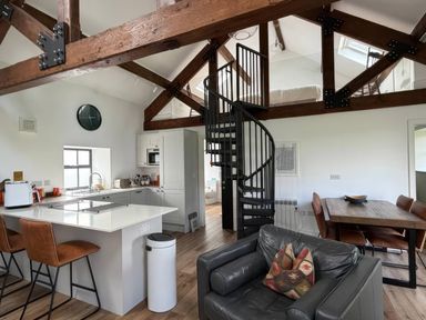 A kitchen with a spiral staircase and dining area at Bank Hurst Coach House in Ulverston