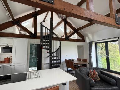 A living room with a spiral staircase and kitchen units at Bank Hurst Coach House in Ulverston