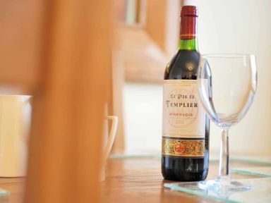 A bottle of red wine and an empty wine glass on a table at House on the Green in Chipping Norton