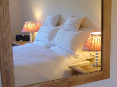 A bedroom with a bed and two bedside tables with lamps at House on the Green in Chipping Norton