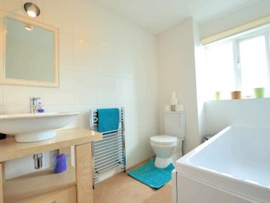 A bathroom with a sink and mirror towel rack toilet and bathtub at House on the Green in Chipping Norton