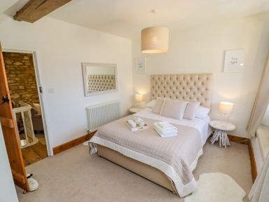 A bedroom with a bed a large mirror on the wall and a side table with a lamp at Chippy Cottage in Chipping Norton