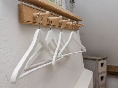 A wooden wall rack with white hangers in a room at Chippy Cottage in Chipping Norton