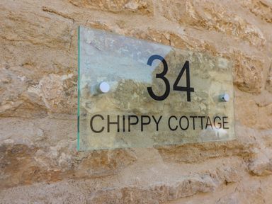 A glass house number sign reading 34 Chippy Cottage on a stone wall at Chippy Cottage in Chipping Norton