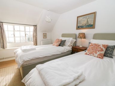 A bedroom with two single beds a bedside table with a lamp and a painting above at Holly Cottage in Minster Lovell