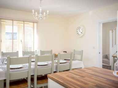 A dining room with a table set for six people with plates and glasses at The Bybrook in Bourton-on-the-Water