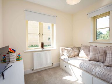 A small room with a sofa bed and a television on a cabinet at The Bybrook in Bourton-on-the-Water