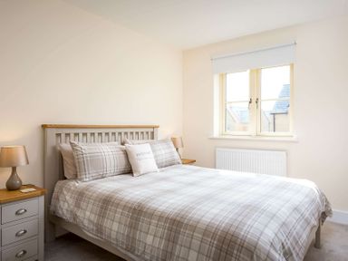 A bedroom with a double bed bedside tables with lamps and a window at The Bybrook in Bourton-on-the-Water