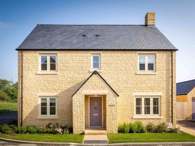 A stone house with a grey door and multiple windows with a small front garden at The Bybrook in Bourton-on-the-Water