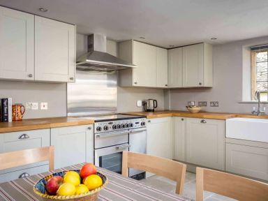 A kitchen with wooden countertops a stainless steel oven a kettle and a bowl of fruit on a table at Shenley Broadwell