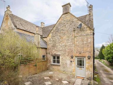 A stone cottage with a small fenced yard and gravel pathway at Shenley in Broadwell
