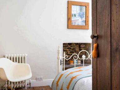 A bedroom corner with a white chair radiator and a bed with a patterned blanket at Little Culver in Minchinhampton
