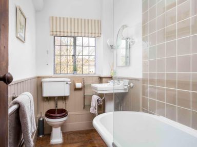 A bathroom with a toilet sink bathtub window and wall tiles at Little Culver in Minchinhampton