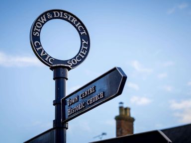 A signpost with directions to town centre and historic church under a blue sky at Stow-on-the-Wold