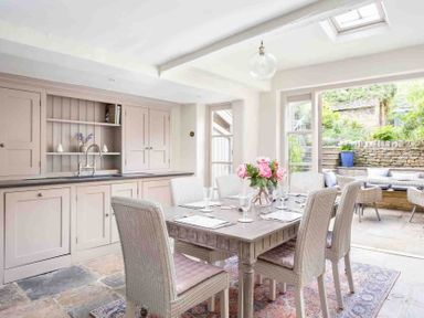 A dining area with six chairs around a table and a built-in cupboard with a sink at Stanley Cottage in Chipping Campden