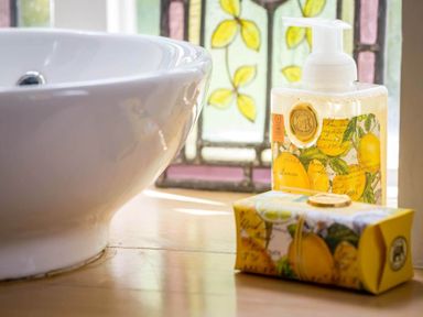 A bathroom sink with soap dispenser and bar soap next to a stained glass window at Stanley Cottage in Chipping Campden