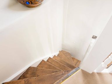 A narrow wooden staircase with white walls at Stanley Cottage in Chipping Campden