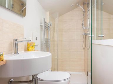 A bathroom with a sink a toilet and a shower area with glass doors at Stanley Cottage in Chipping Campden