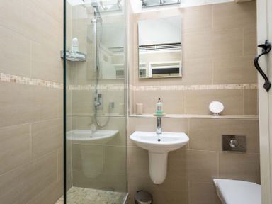A bathroom with a shower, a sink with soap and a mirror at Lanes Cottage in Chipping Campden