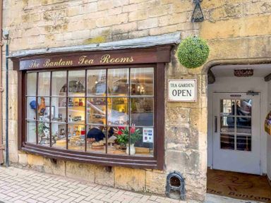 The exterior of The Bantam Tea Rooms with a large window displaying cakes and a sign that says tea garden open in Chipping Campden