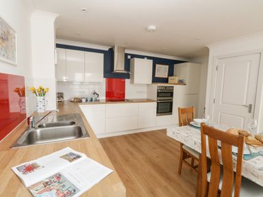 A kitchen with wooden countertops white cabinets dining table with wooden chairs and red and white tiled backsplash at Pebbles Reach in Fortuneswell